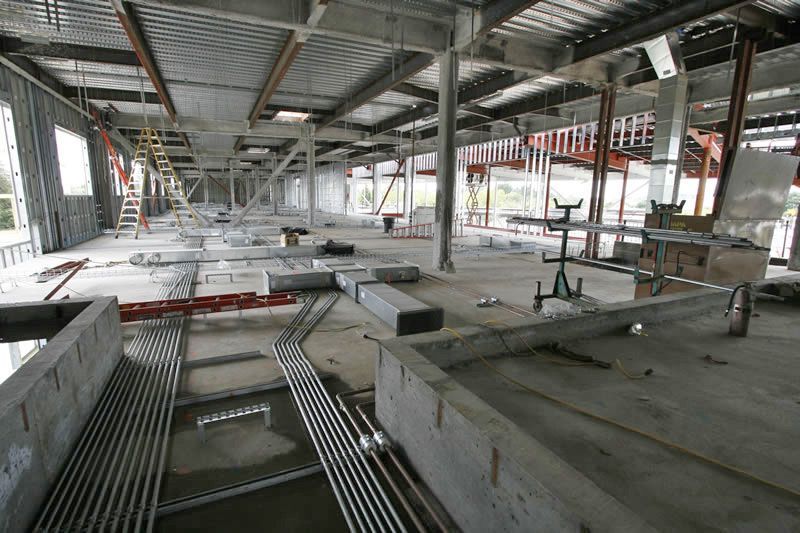 Abandoned industrial building interior with unfinished concrete floors, metal beams, and scattered construction materials