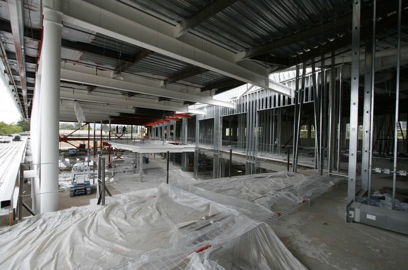 Interior of a construction site with steel framing, covered floors, and a partially built roof.