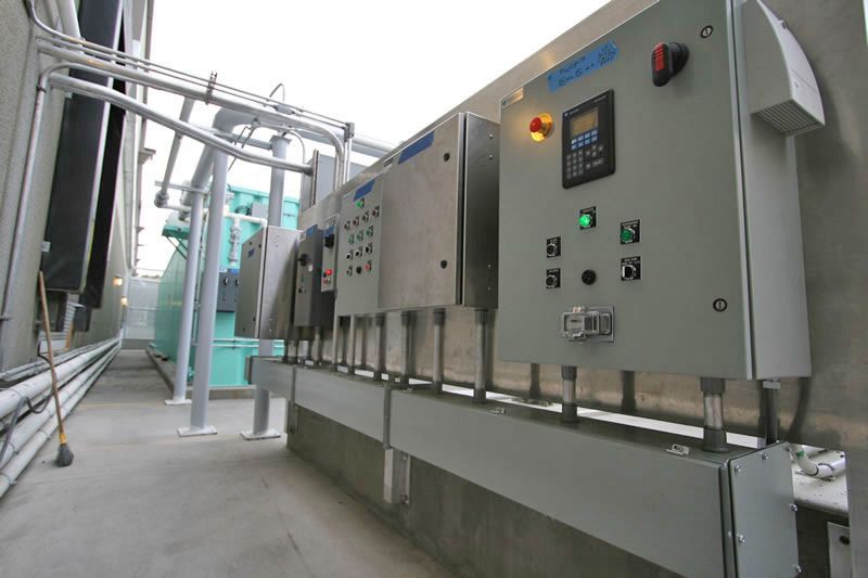 Industrial processing line with stainless steel machinery, control panels, and pipes in a factory room