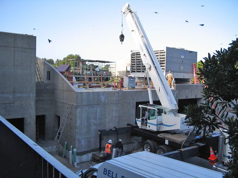 Construction site with crane lifting materials over a concrete building foundation.