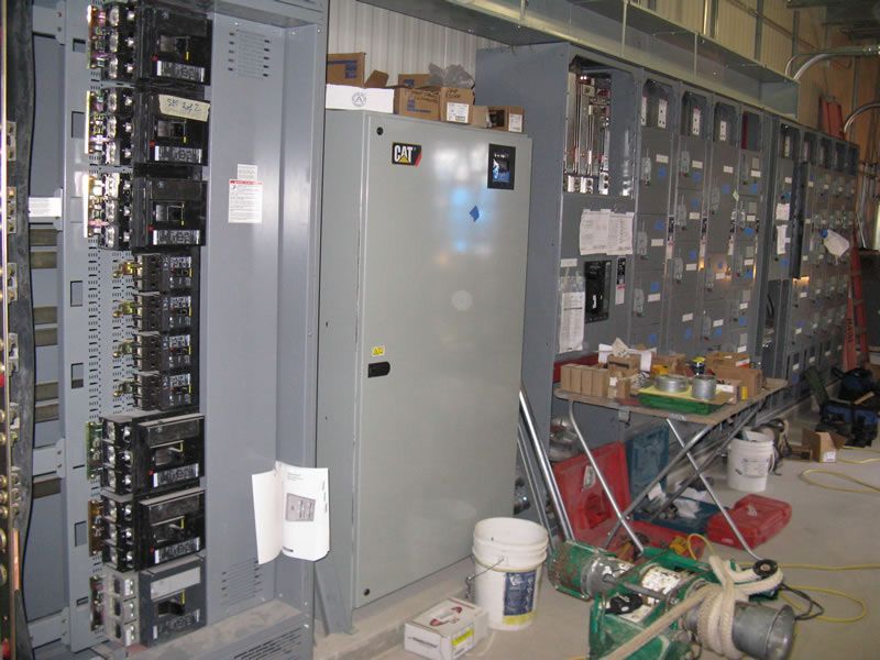 Electrical control room with gray cabinets, exposed panels, and maintenance tools on the floor