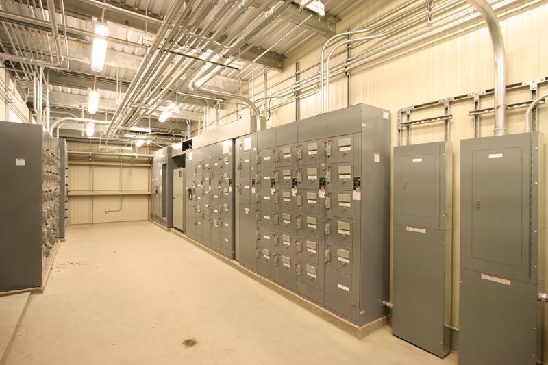 Industrial electrical room with gray control cabinets and exposed ceiling piping