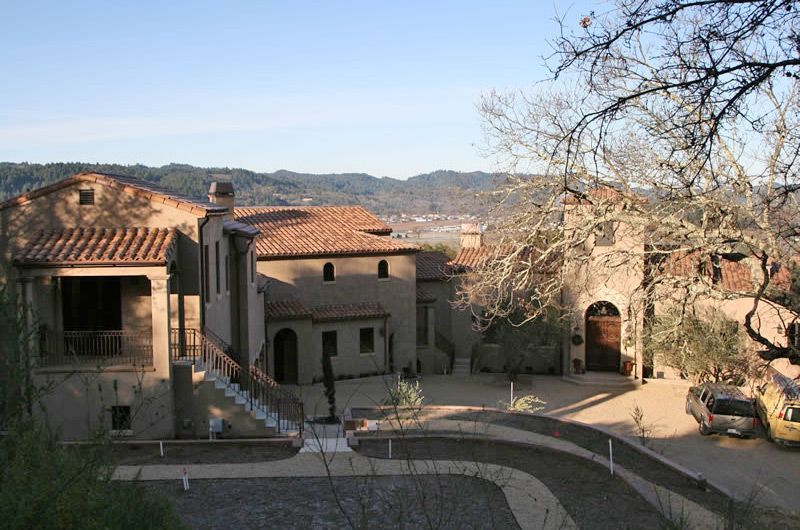 Stone courtyard with rustic Mediterranean buildings and red-tile roofs under a clear sky