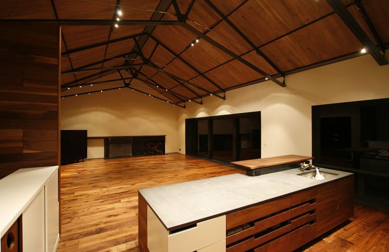 Empty modern kitchen with wood floors, high vaulted ceiling, and white countertops
