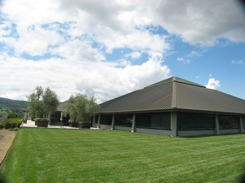 Large grassy lawn beside a low gray building under a partly cloudy sky