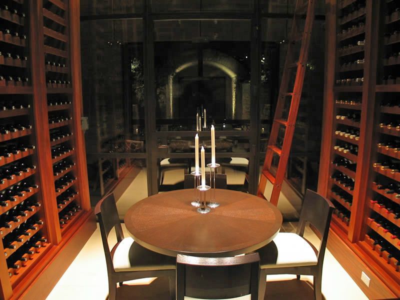 Elegant wine cellar with a round wooden table, chairs, and wall-to-wall wine racks