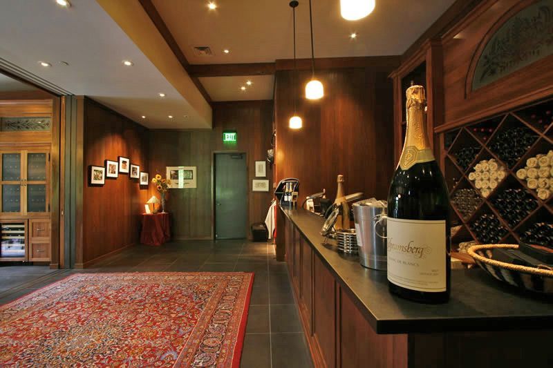 Wine cellar with bottles on a counter, warm lighting, and a patterned rug in a cozy room