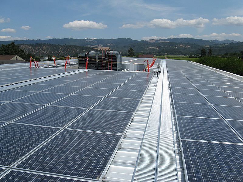 Rooftop covered with solar panels under a clear sky, with mountains in the distance.