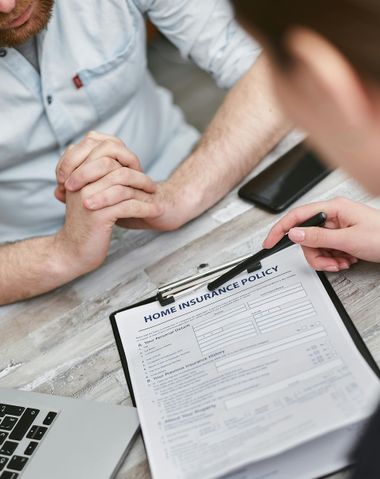 Hands signing a document during a meeting, with a pen and laptop on a desk.