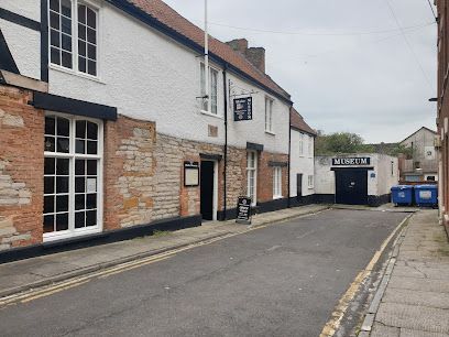 Quiet narrow street with white brick buildings, parked bins, and overcast sky