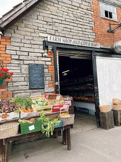 Farm shop entrance with produce stands and flowers outside a stone building