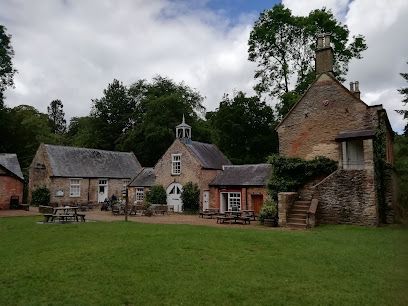 Stone cottages and a rustic farmhouse around a grassy courtyard under a cloudy sky