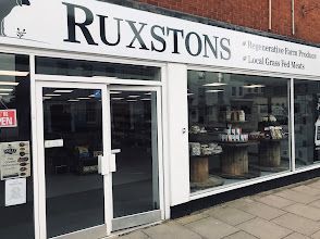 Storefront of RUXSTONS bakery with glass doors and display windows on a city sidewalk.