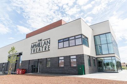 Exterior of The Millian Theatre, a modern white building with black and glass accents under a blue sky
