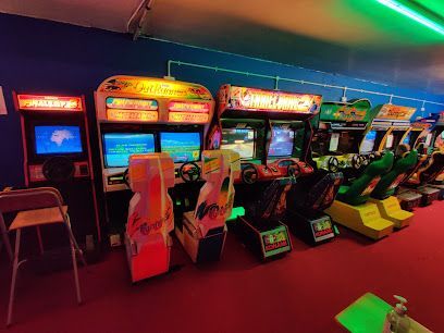 Rows of colorful arcade racing game cabinets in a dimly lit arcade room