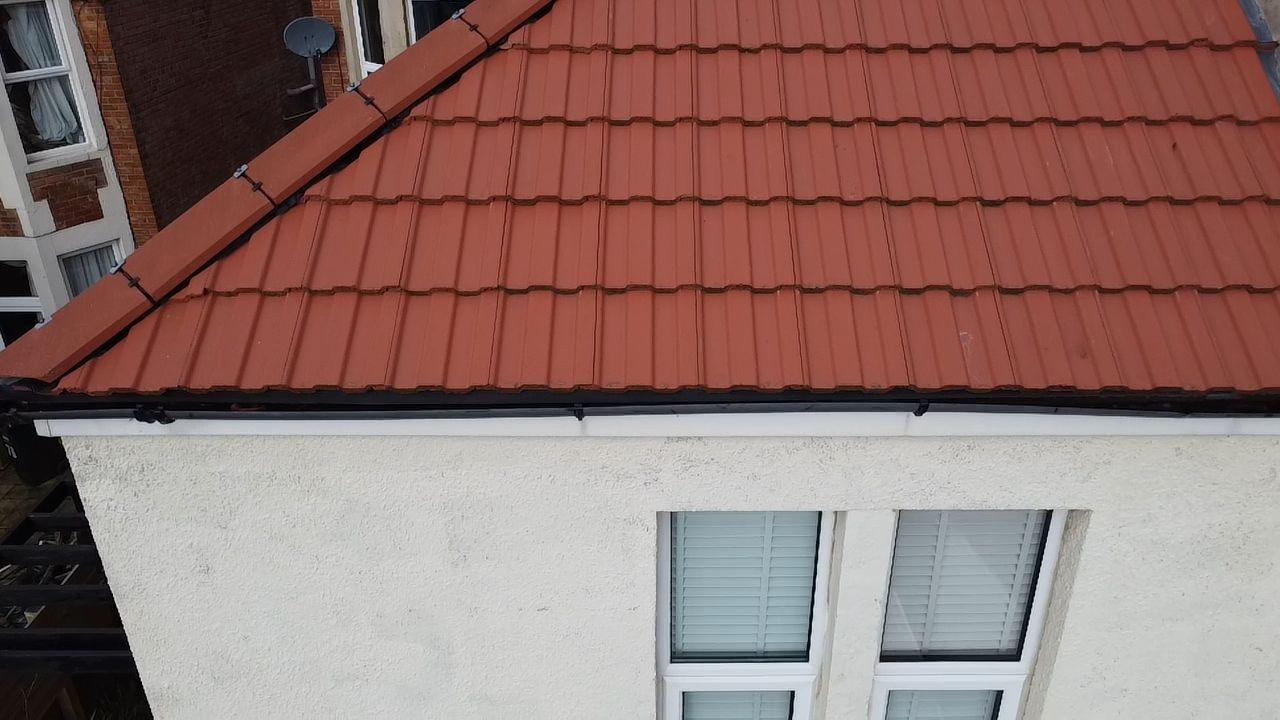 Red tiled roof above a white house wall with a pair of windows