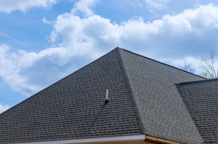 Gray shingled roof against a blue sky with clouds