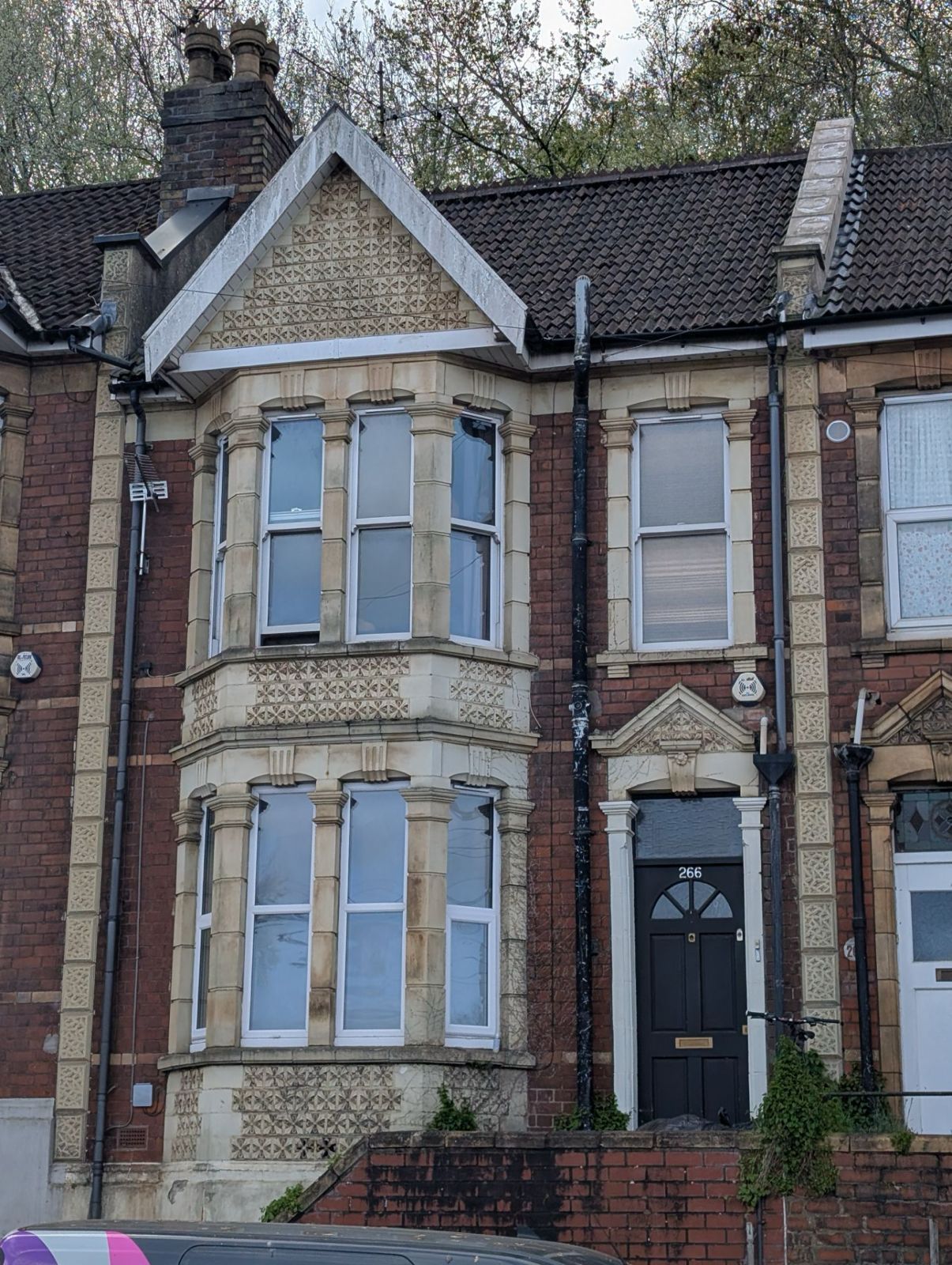 Victorian brick townhouse with bay windows, a dark front door, and a small front garden