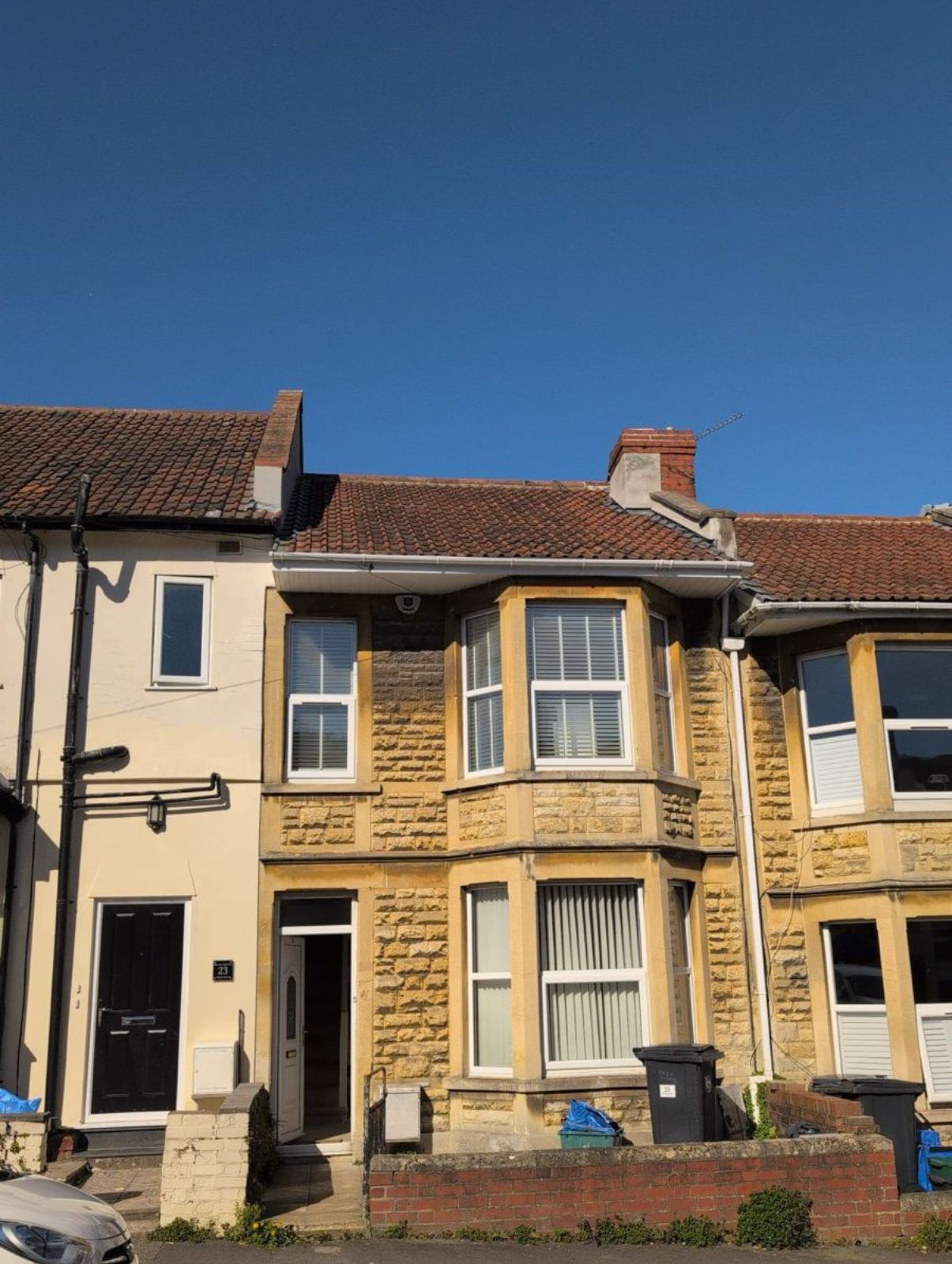 Row of cream-colored terraced houses with red-tiled roofs under a clear blue sky