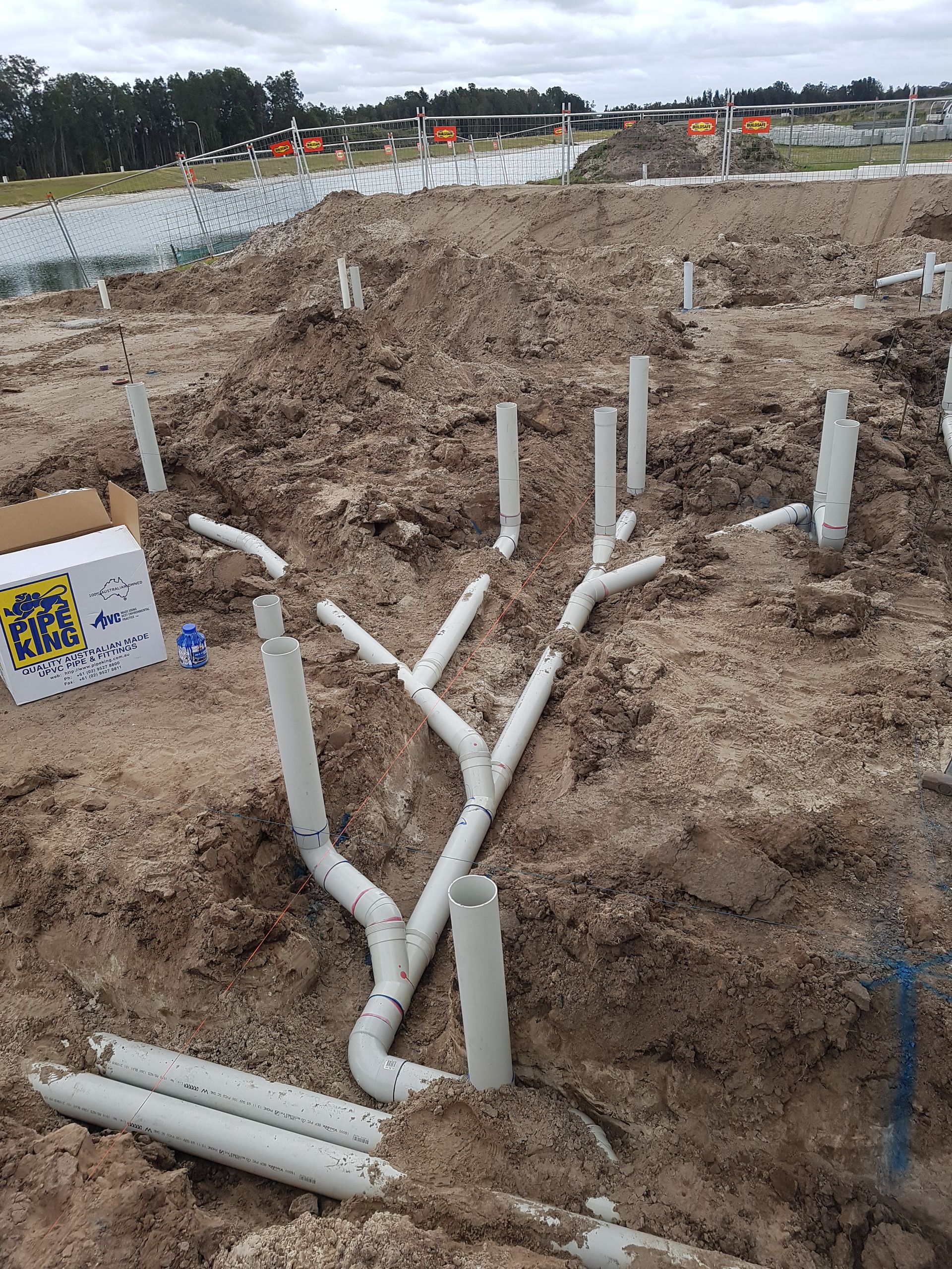 A Bunch of Pipes Are Laying in the Dirt on a Construction Site — Bevan Plumbing in South Lismore, NSW