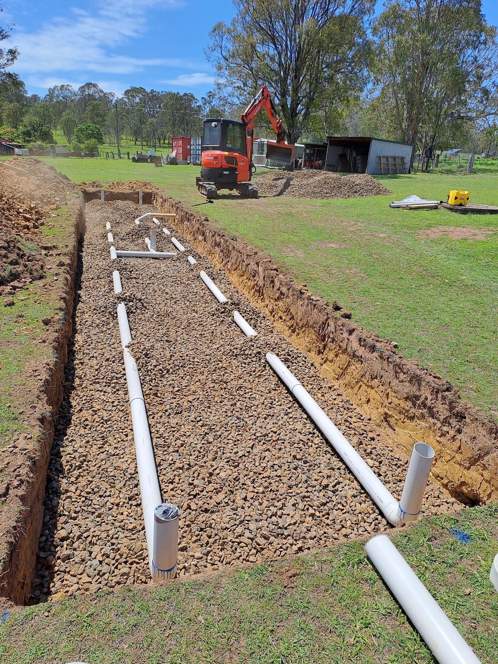 A Row of Pipes Are Being Installed in the Dirt in a Field — Bevan Plumbing in South Lismore, NSW
