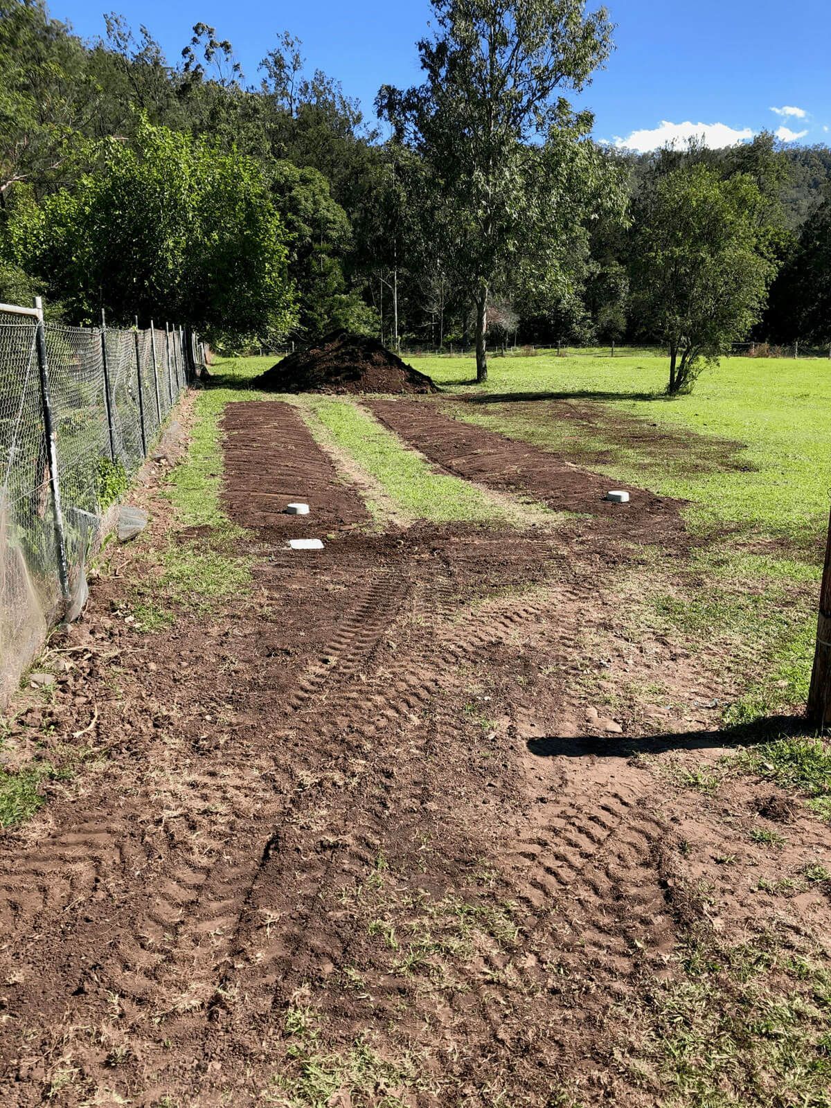 A Dirt Road Going Through a Grassy Field With a Fence in the Background — Bevan Plumbing in South Lismore, NSW