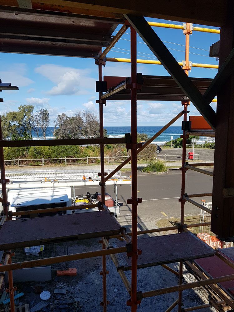 A Construction Site With Scaffolding and a View of the Ocean — Bevan Plumbing in Byron Bay, NSW