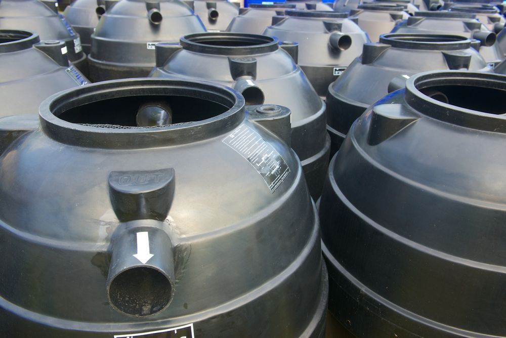 A Bunch of Black Plastic Containers Are Stacked on Top of Each Other — Bevan Plumbing in Lismore, NSW