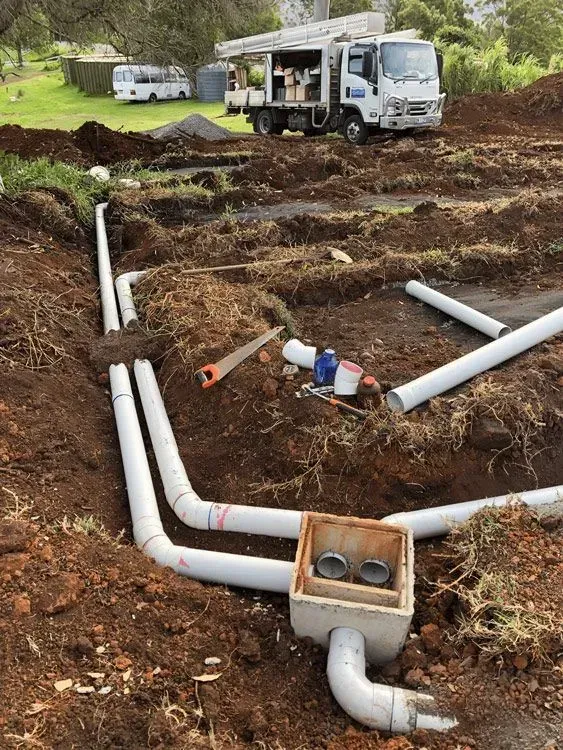 A Truck is Parked in the Dirt Next to a Pile of Pipes — Bevan Plumbing in Alstonville, NSW
