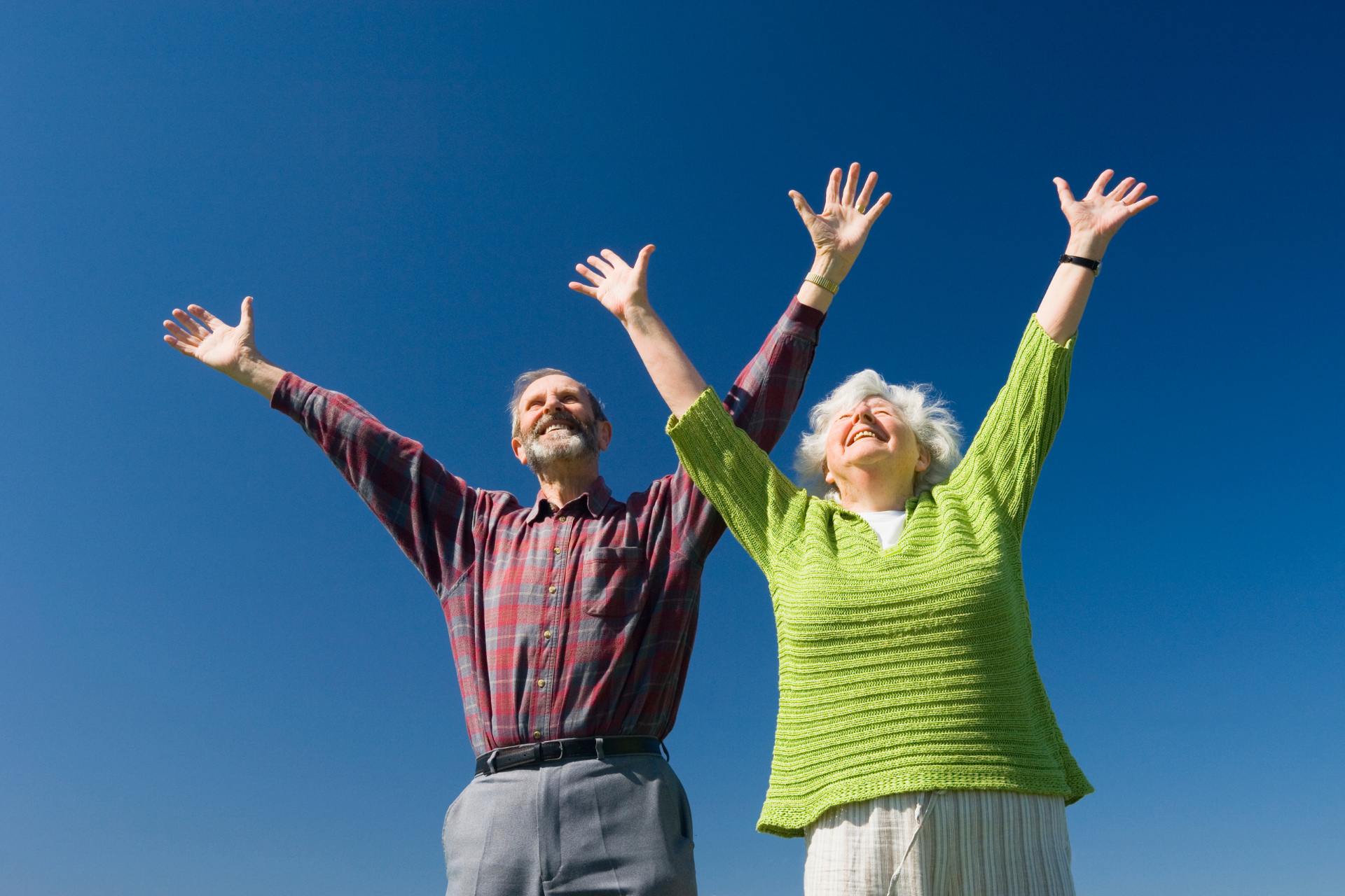 A man and a woman are standing with their arms in the air.