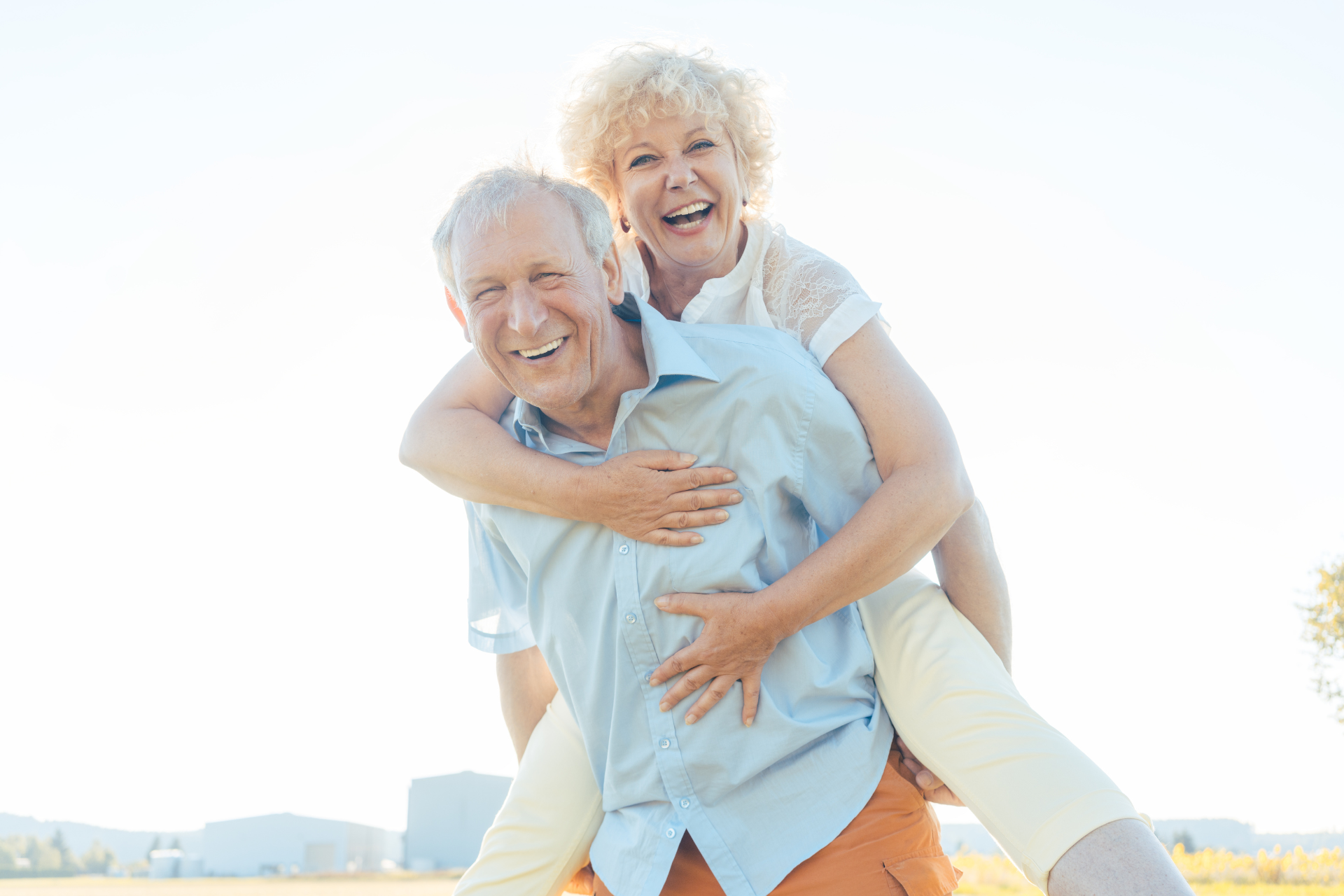 A man is carrying a woman on his back in a field.