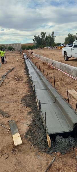 Construction site with a concrete trench being built in an open field.