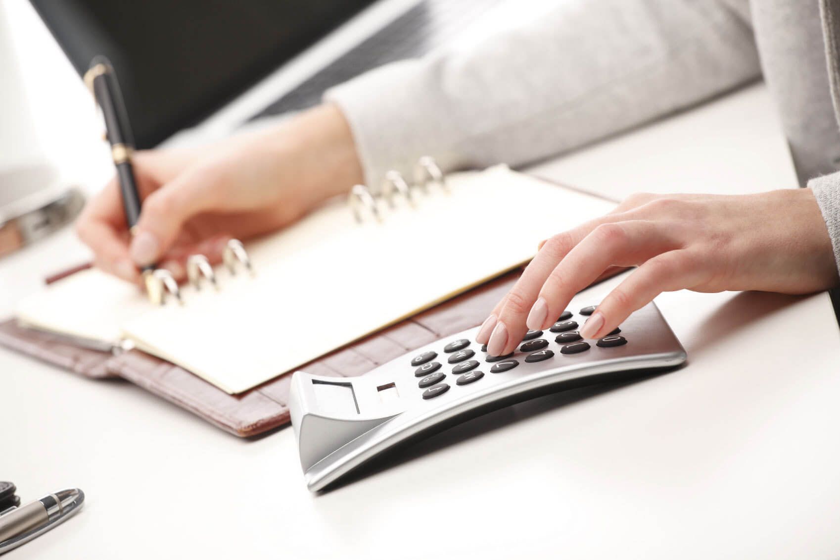 CPA crunching numbers on calculator and writing in notebook