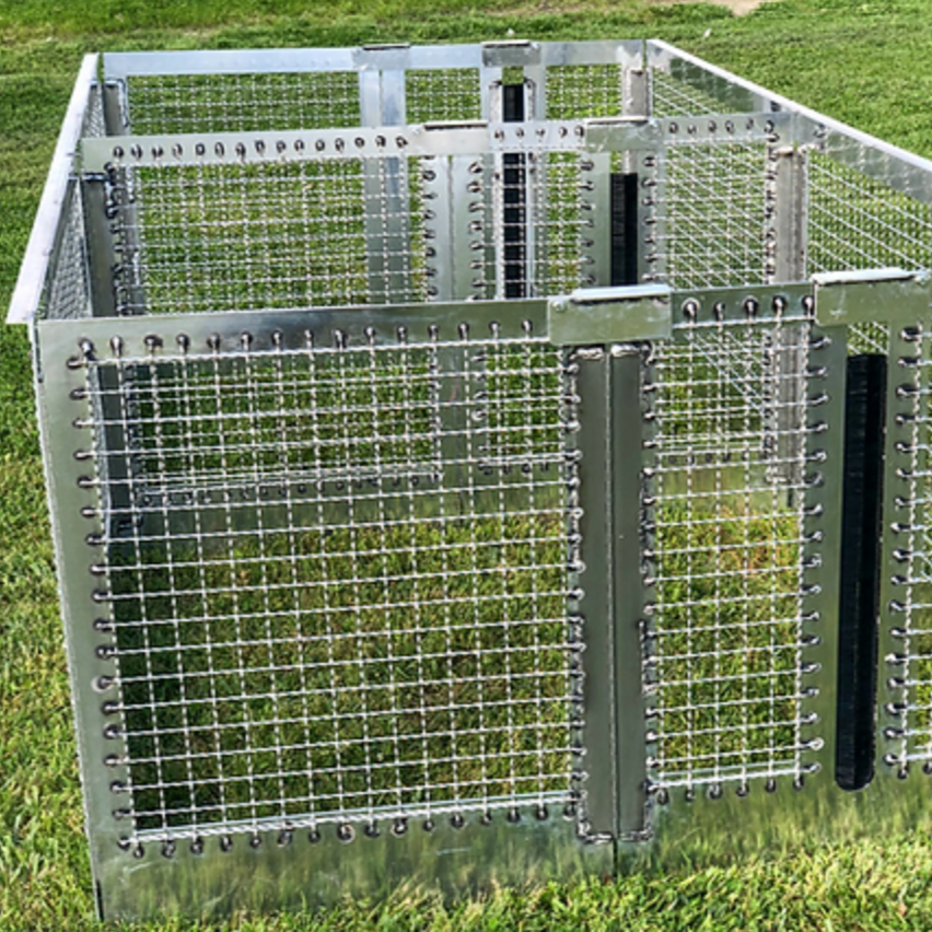 Metal wire and frame cage on grass; likely for animals or containment.