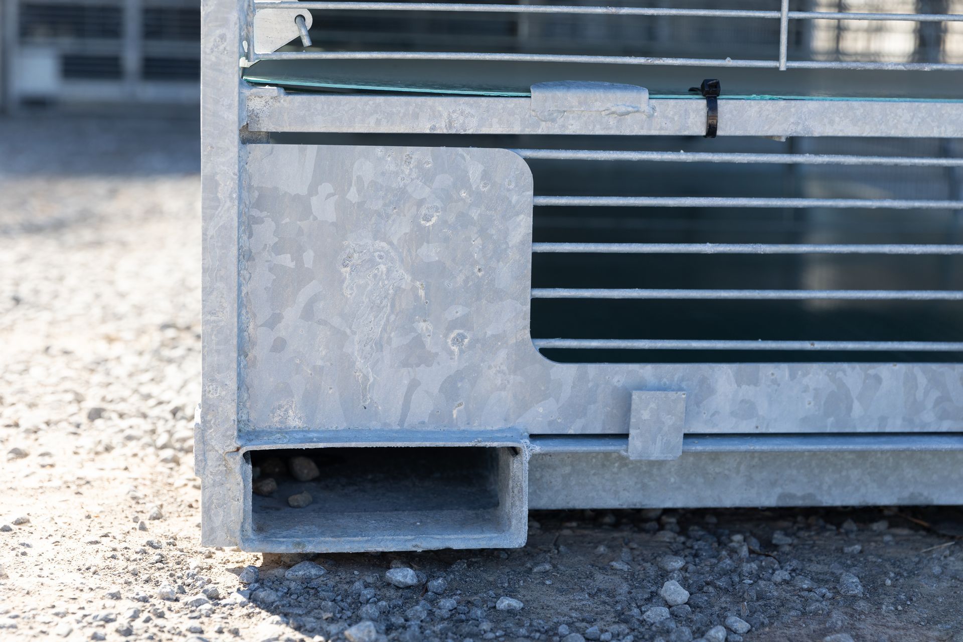 Close-up of a metal structure corner with a rectangular opening and horizontal grates.