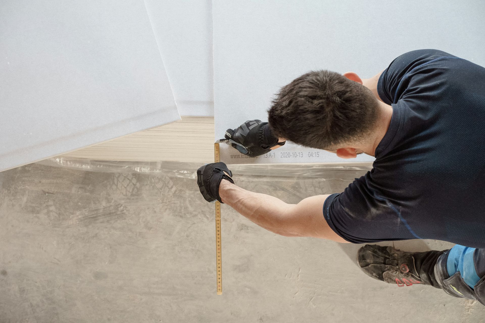 Worker measuring a concrete wall with a tape measure during construction