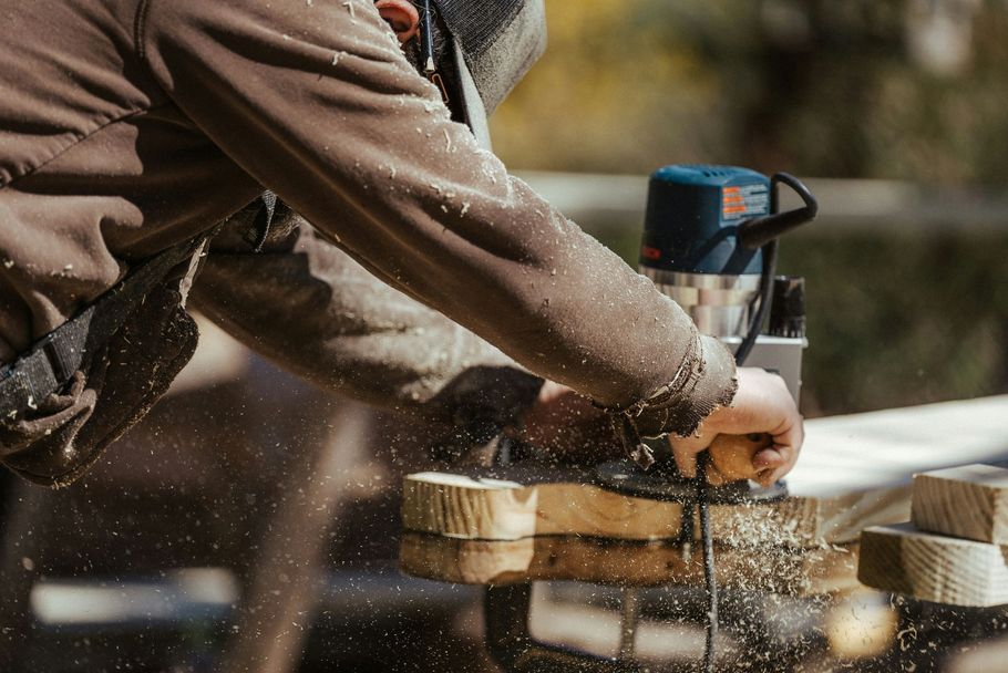 Person sawing wood with a circular saw, sending sawdust into the air outdoors