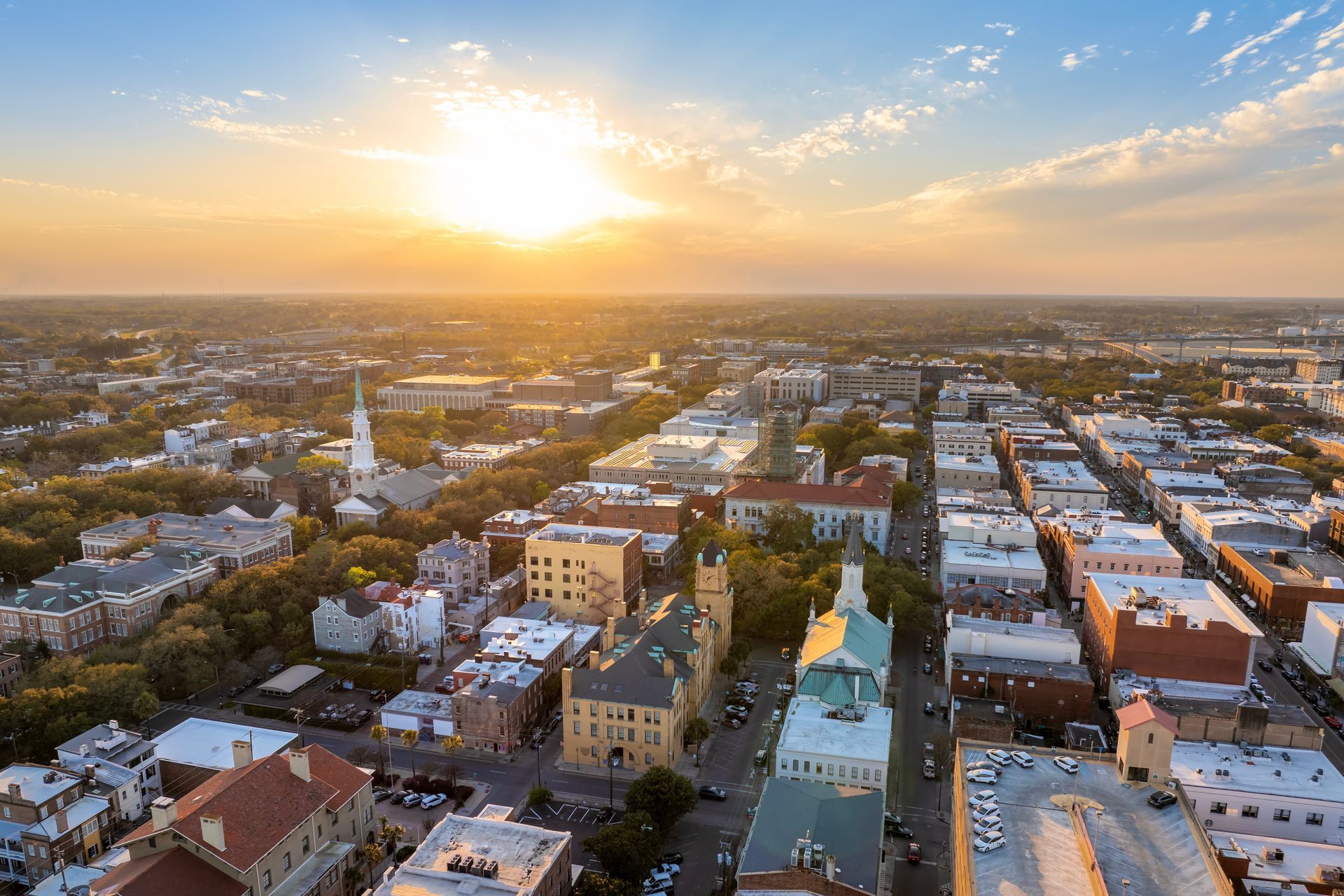 Aerial view of Savannah, Georgia at sunset with a cityscape of buildings and a church steeple. Aerial view of Savannah, Georgia at sunset with a cityscape of buildings and a church steeple.