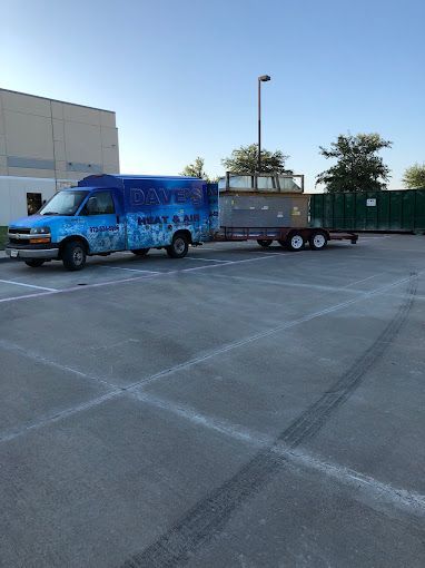 A blue van is parked in a parking lot with a trailer attached to it