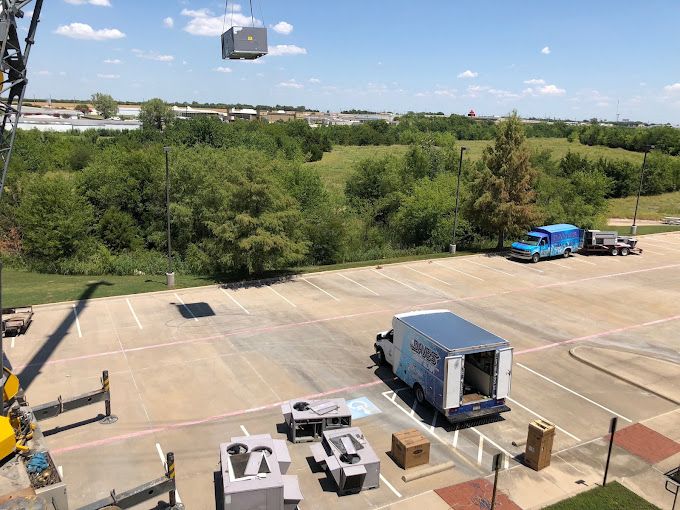 A crane is lifting a piece of equipment in a parking lot.