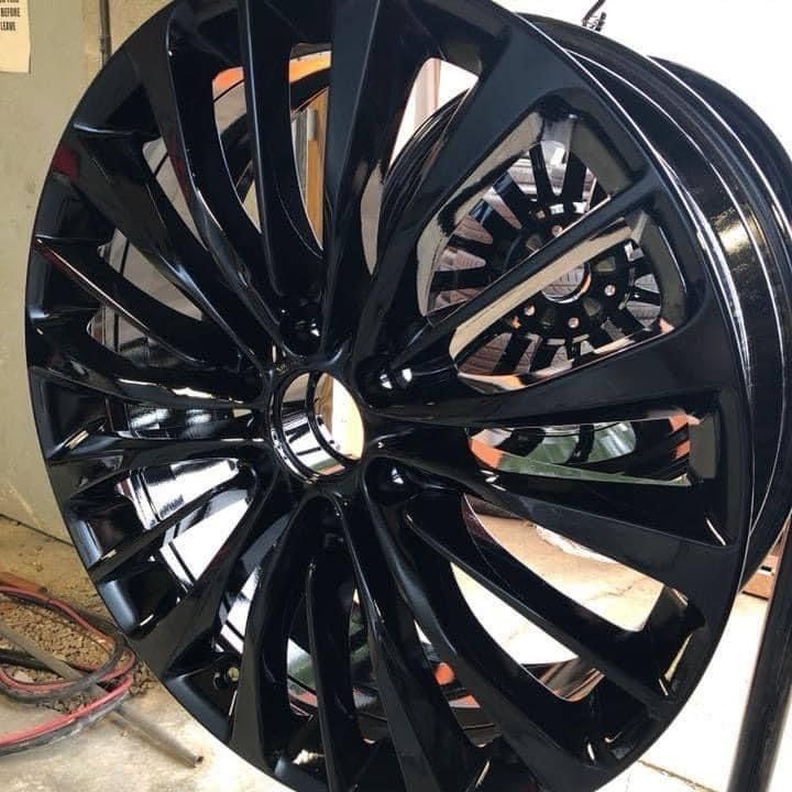 Black car wheel with a glossy finish, reflecting light.