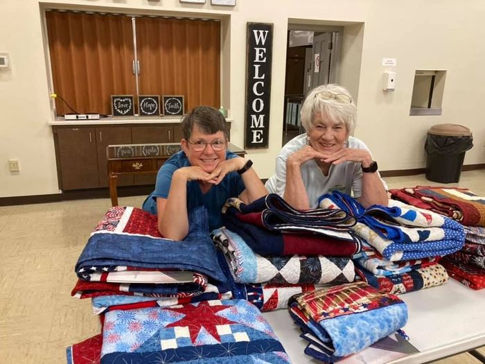 Image of 2 women leaning on quilts