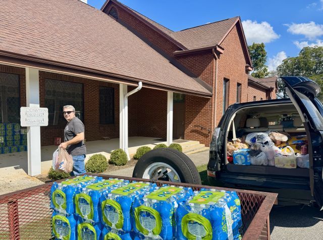 A man is loading toilet paper into the back of a truck.