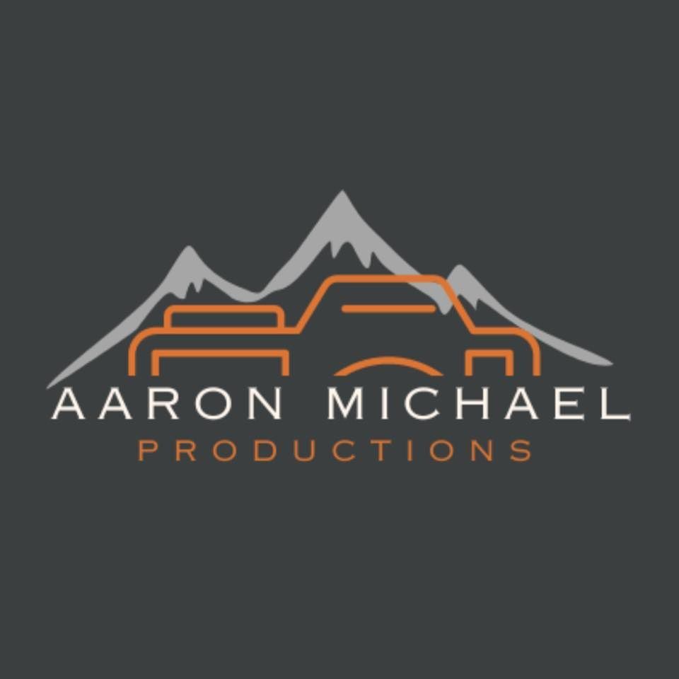 Logo for Aaron Michael Productions featuring an orange camera outline set against grey mountain peaks on a dark background.