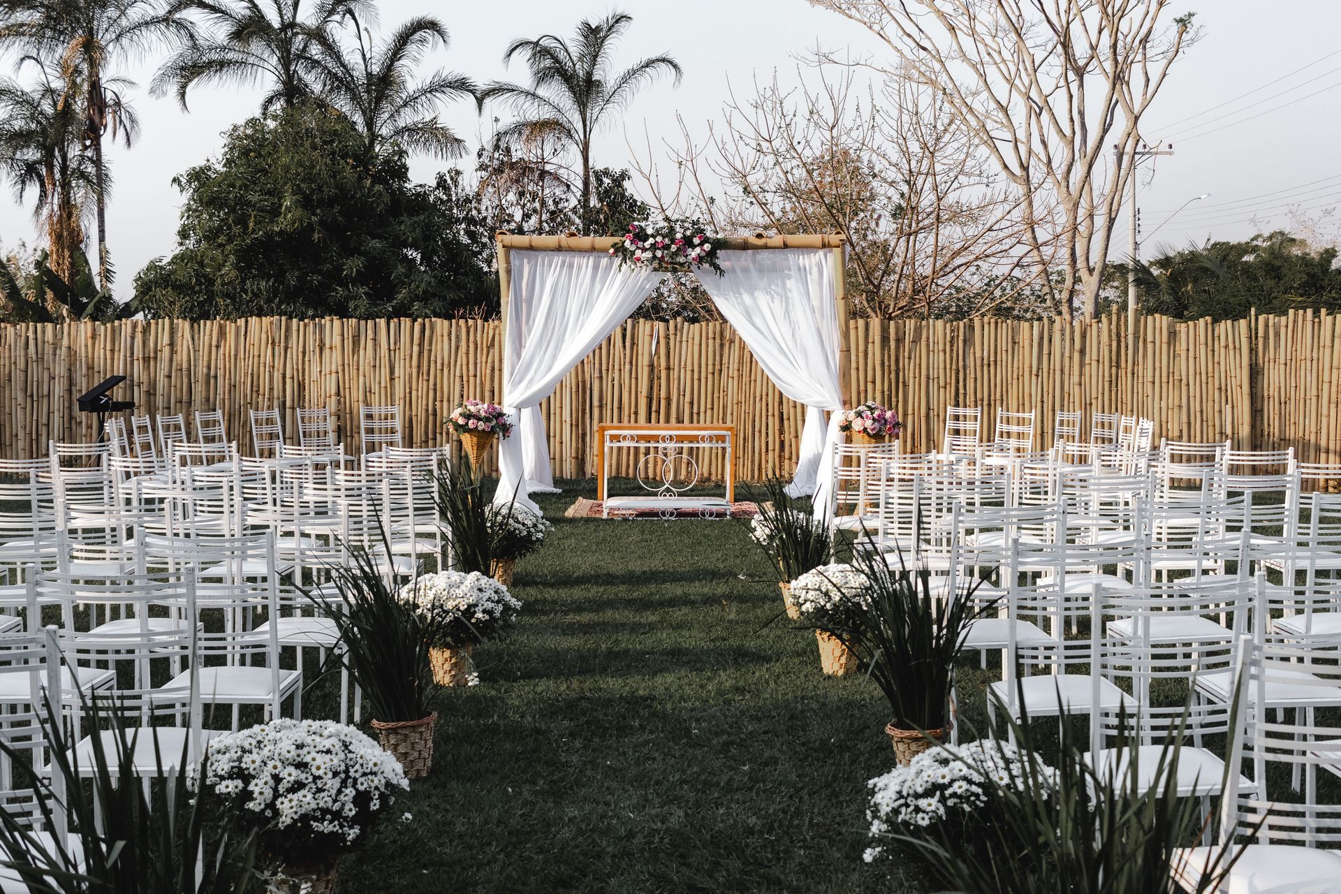 Outdoor wedding aisle with white chairs and a floral arch at the altar