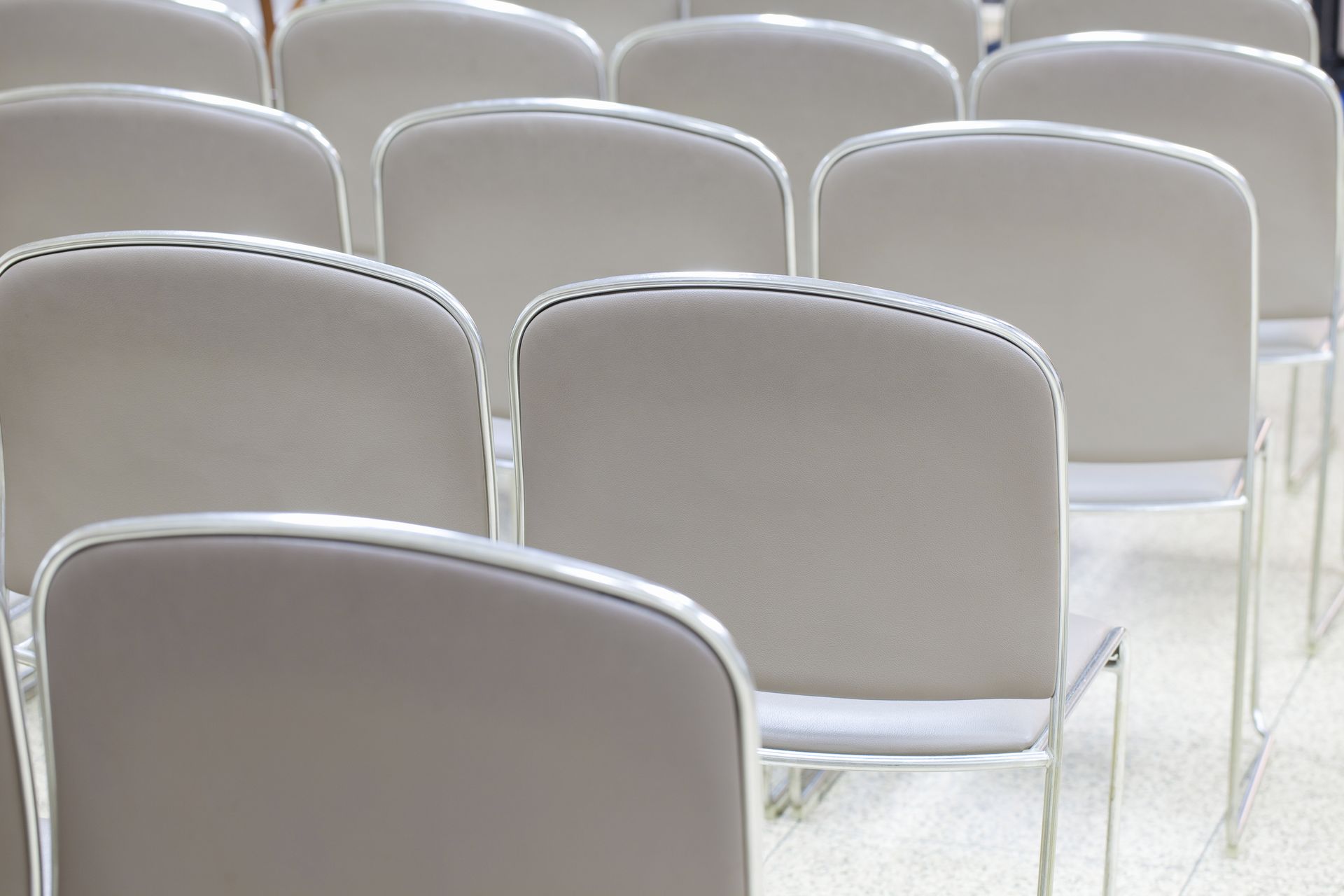 Rows of empty gray chairs arranged in an auditorium or conference room
