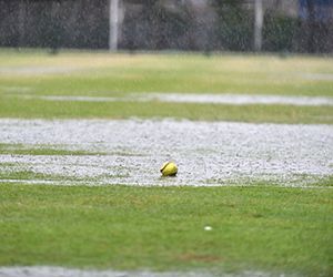 Softball on wet grass in a rainy field