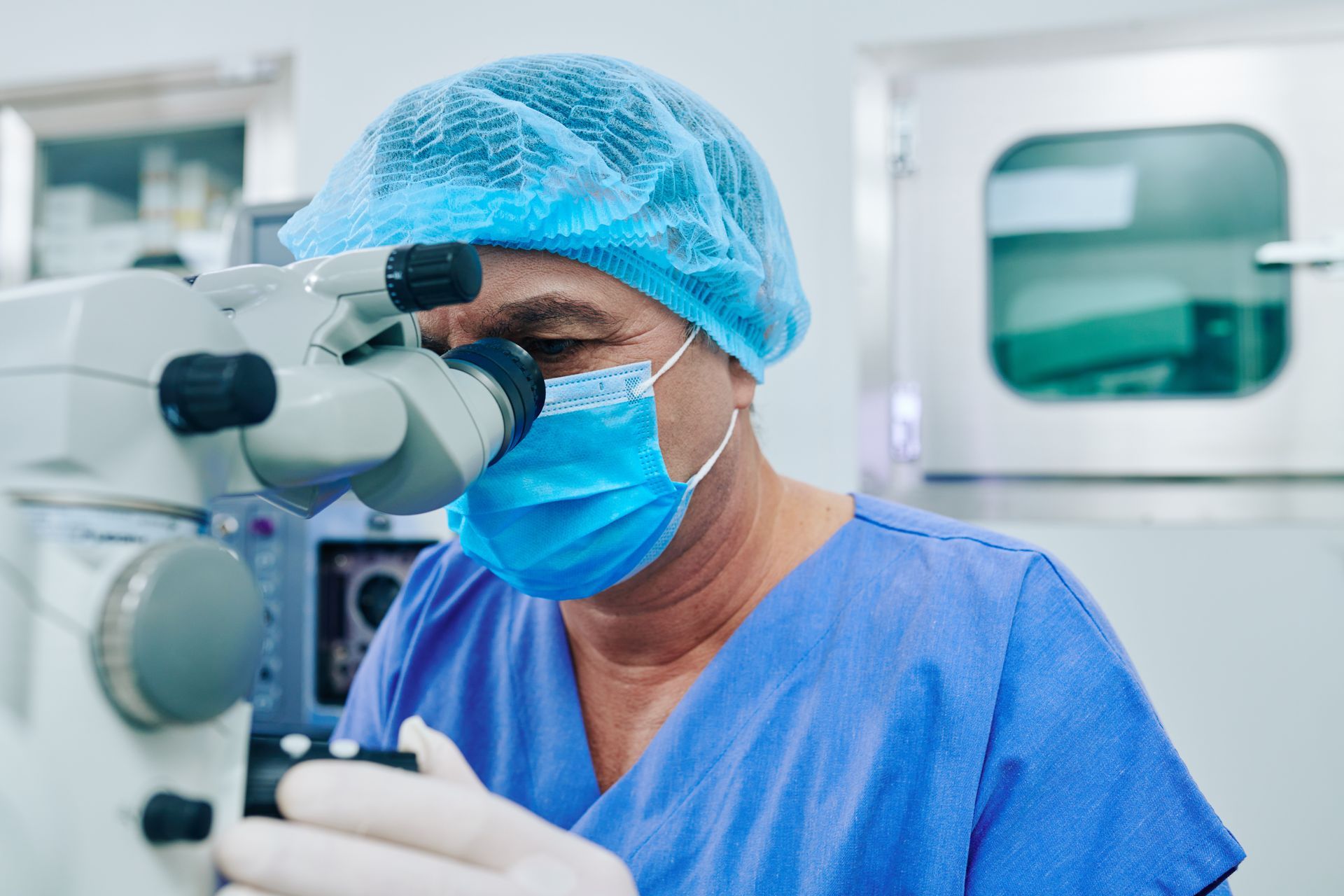 Un chirurgo osserva attraverso un microscopio in una sala operatoria.