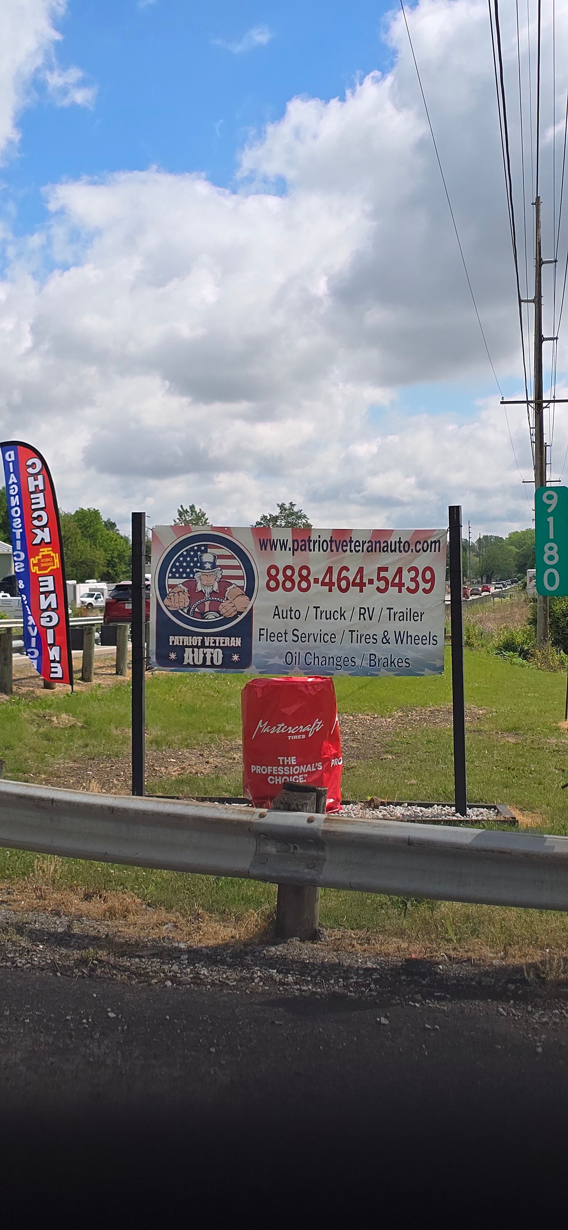 Roadside real estate signs behind a metal guardrail under a cloudy sky