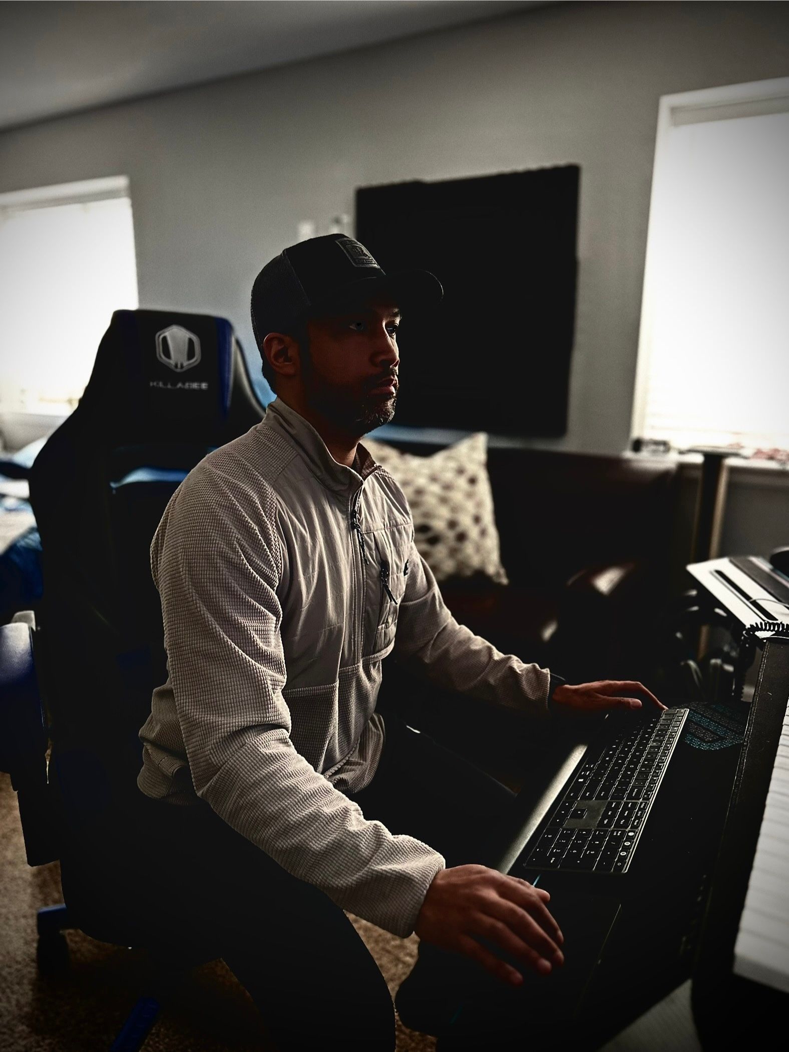 A man is kneeling down in front of a keyboard in a living room.